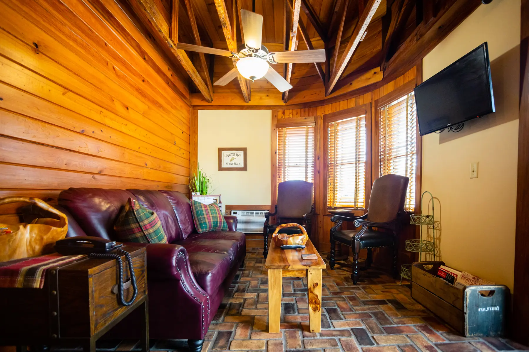 Cozy wooden cabin living room with leather seating and warm lighting.