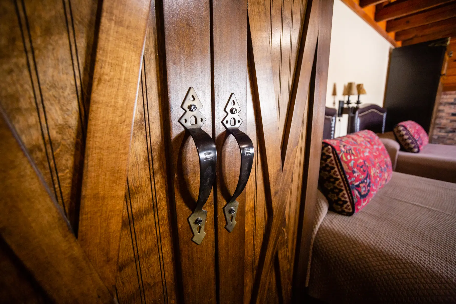 Elegant wooden closet doors with ornate handles in a cozy bedroom.
