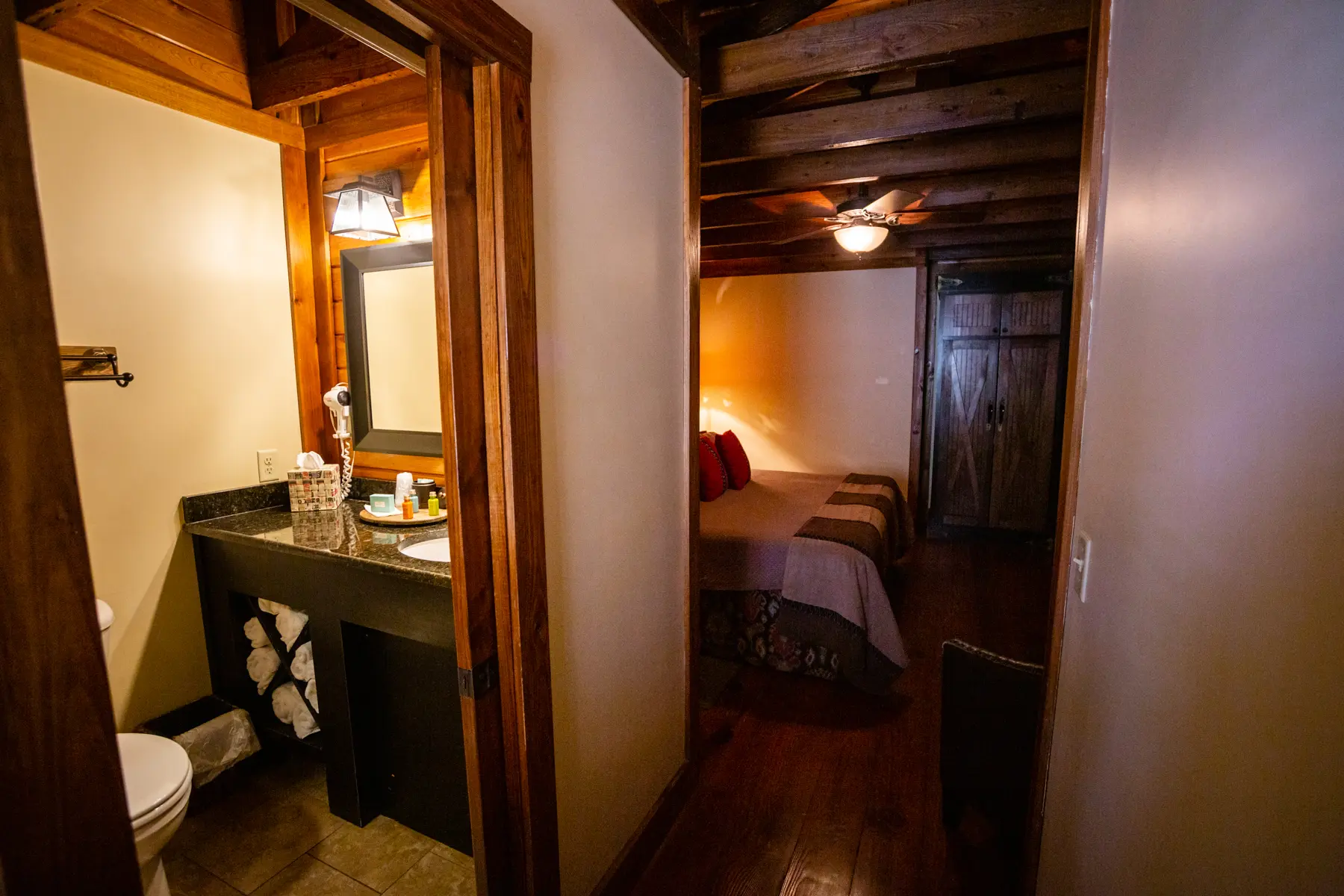 Warm, rustic bedroom and bathroom area with wooden beams and cozy lighting.