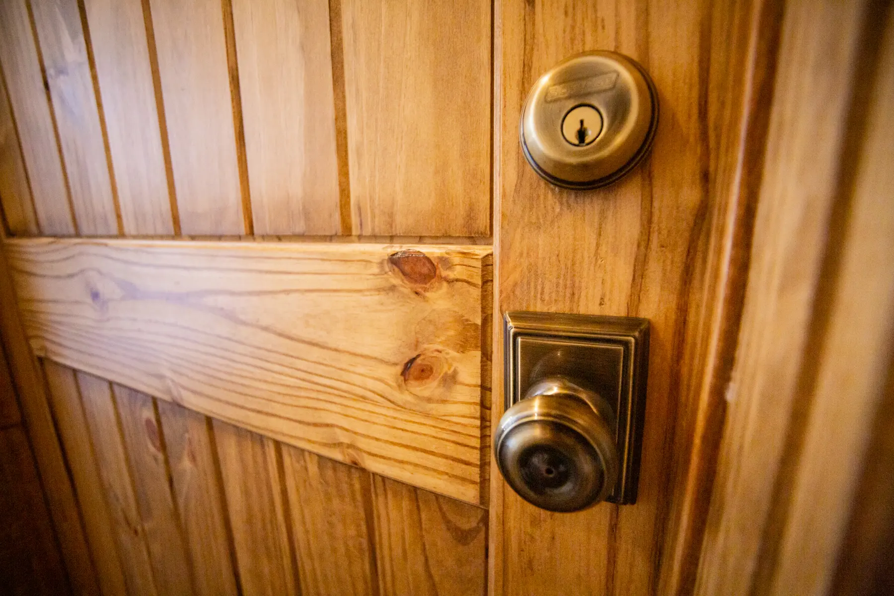 Close-up of a wooden door with a brass doorknob and lock.