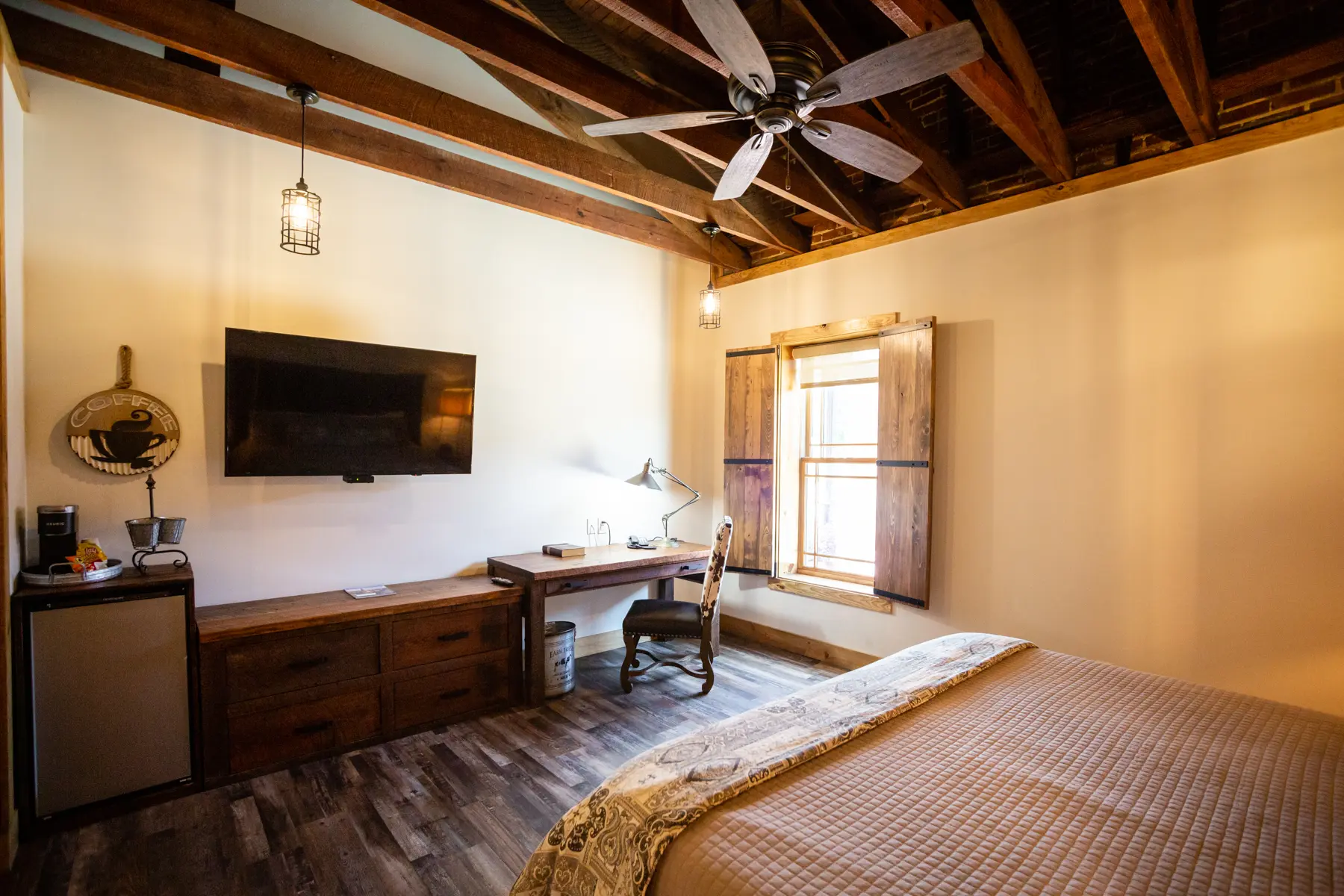 Cozy bedroom with wooden beams, large window, and a desk workspace.