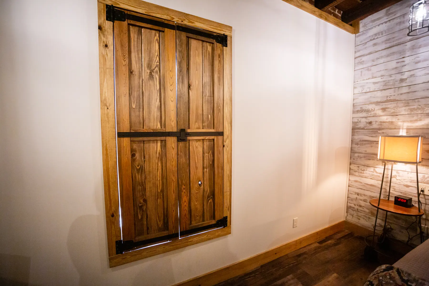 Closed wooden window shutters on a white wall inside a room.