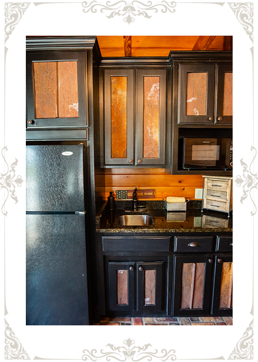 Rustic kitchen with wooden cabinets and a black refrigerator.